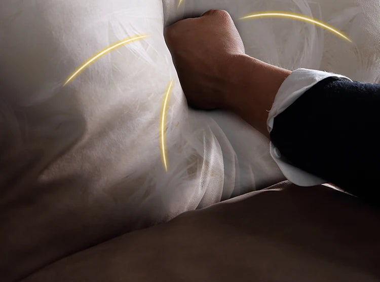 Person lying on a bed with a white comforter, hand resting on pillow