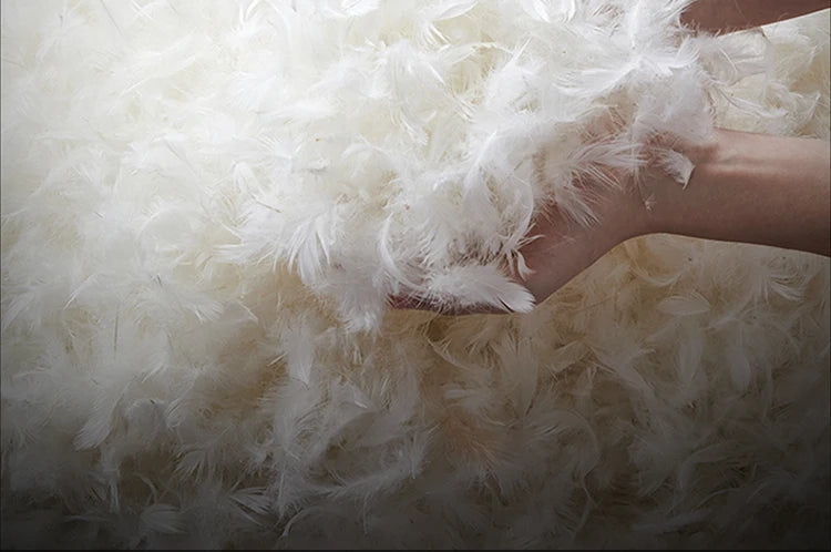 Close-up of white feathers held by a hand against a fluffy white background