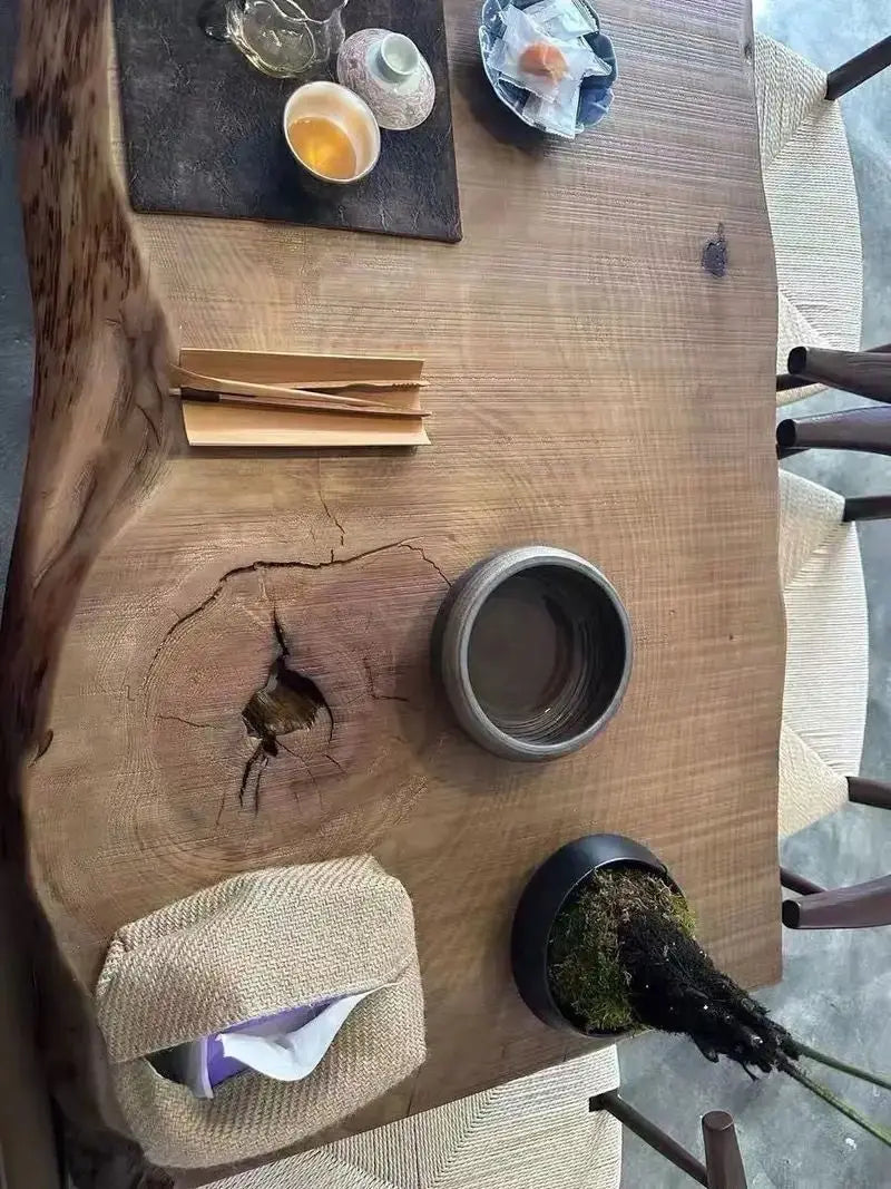 Wooden table with a rustic design, featuring a small pot and a piece of paper on it.