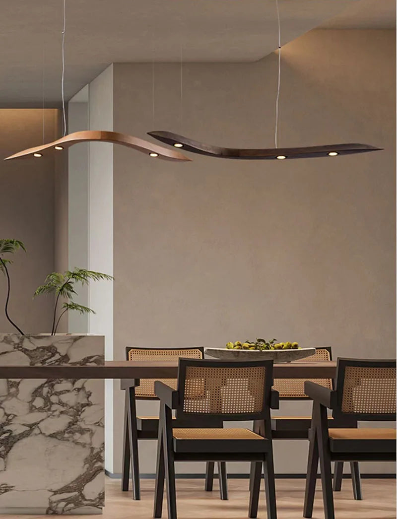 Modern dining room with a long table and chairs, featuring a stylish pendant light.