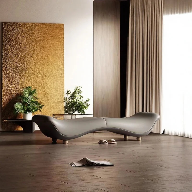 Modern living room with a curved gray sofa, plants, and a large window.