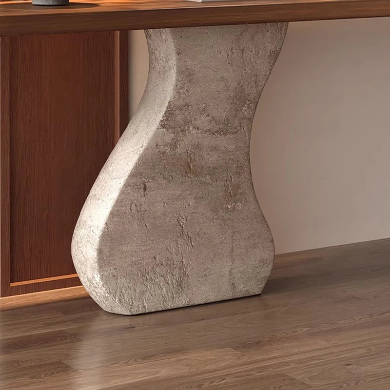 Close-up of a wooden table with a stone-like base against a neutral wall.