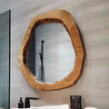 Wooden-framed mirror on a bathroom wall with a sink and faucet in the background.
