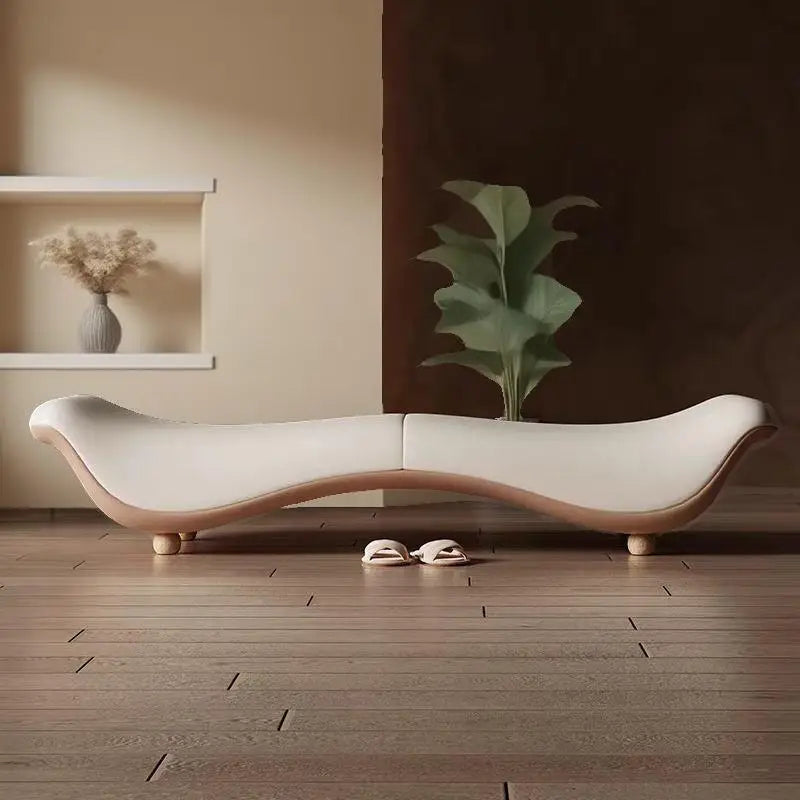 Modern white sofa with wooden legs in a minimalistic room with a plant and shelf.