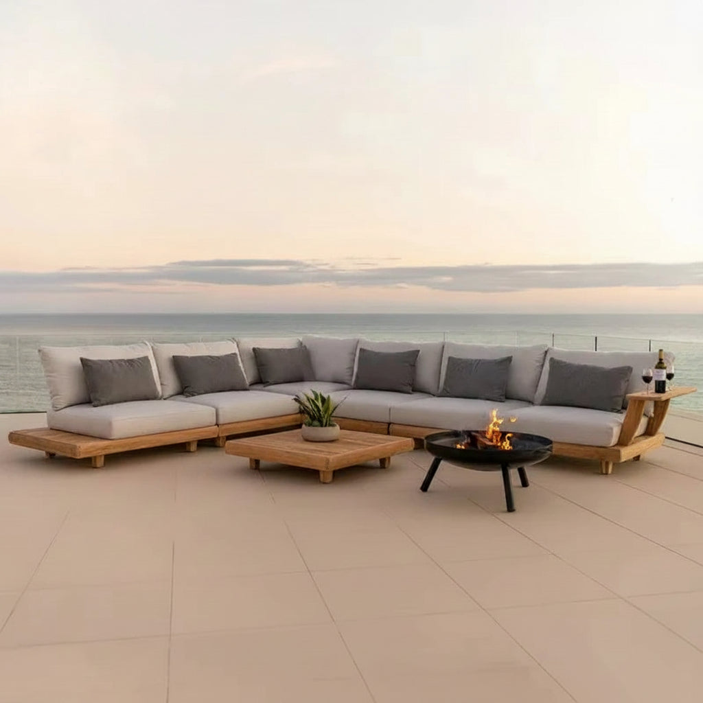 Outdoor patio furniture set with a fire pit table on a deck overlooking the ocean.