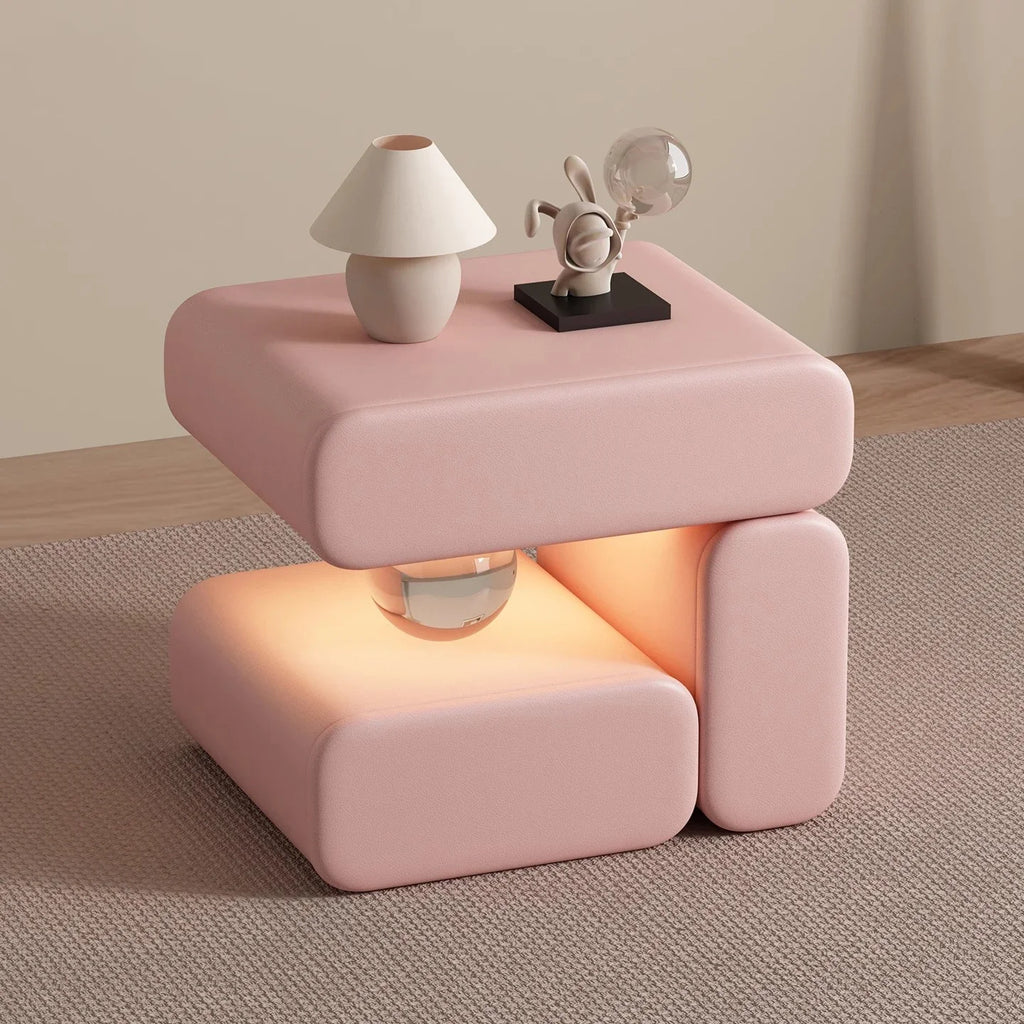 Pink side table with a lamp and decorative object on a neutral background