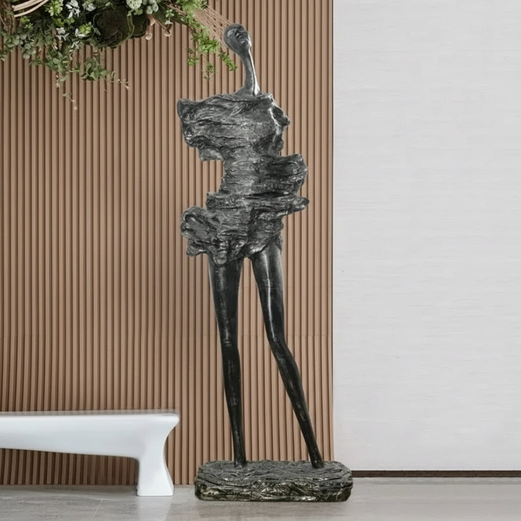 Abstract sculpture on a pedestal against a neutral wall with a bench and decorative elements.