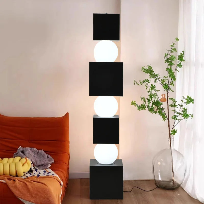 Modern floor lamp with black and white design in a room with a bed and plant.