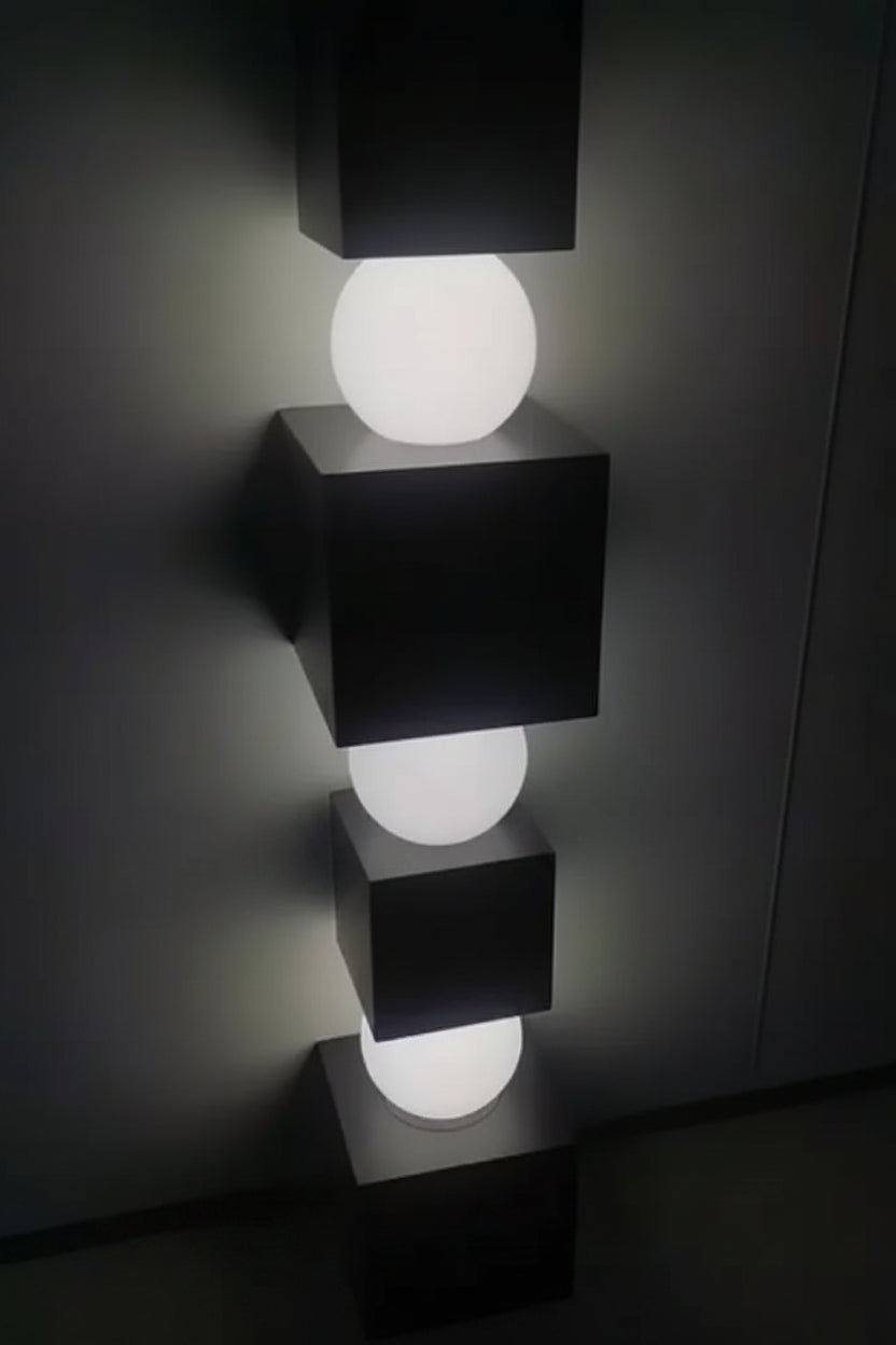 Modern wall-mounted light fixture with black square bases and white spherical lights on a dark background.