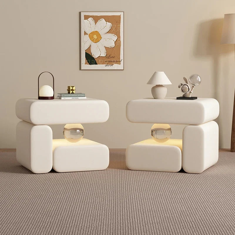 Two modern white side tables with decorative items in a room setting.