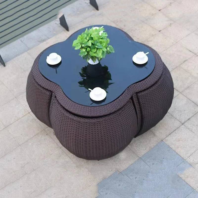 Round outdoor coffee table with glass top and decorative items on a patio.