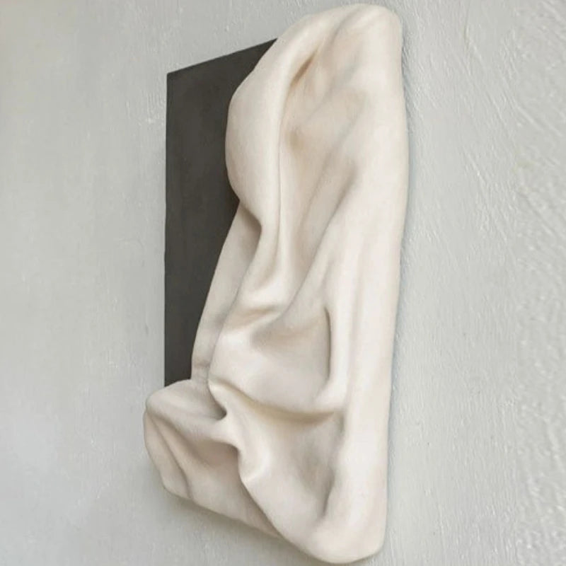 White fabric draped over a black rectangular object on a light gray background