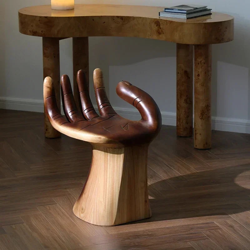 Wooden chair designed like a hand in front of a wooden table.