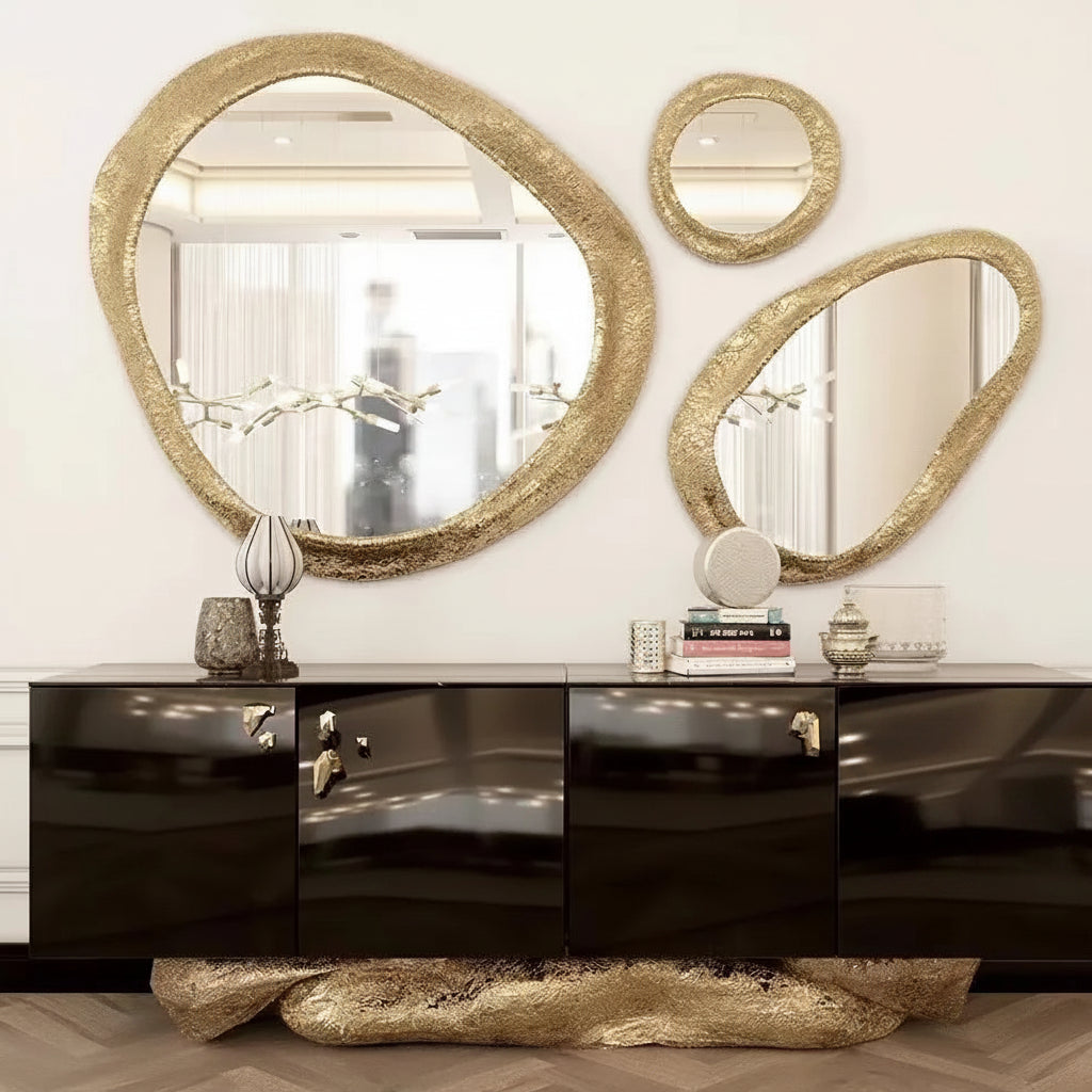 Decorative mirrors with gold frames on a white wall above a black cabinet.