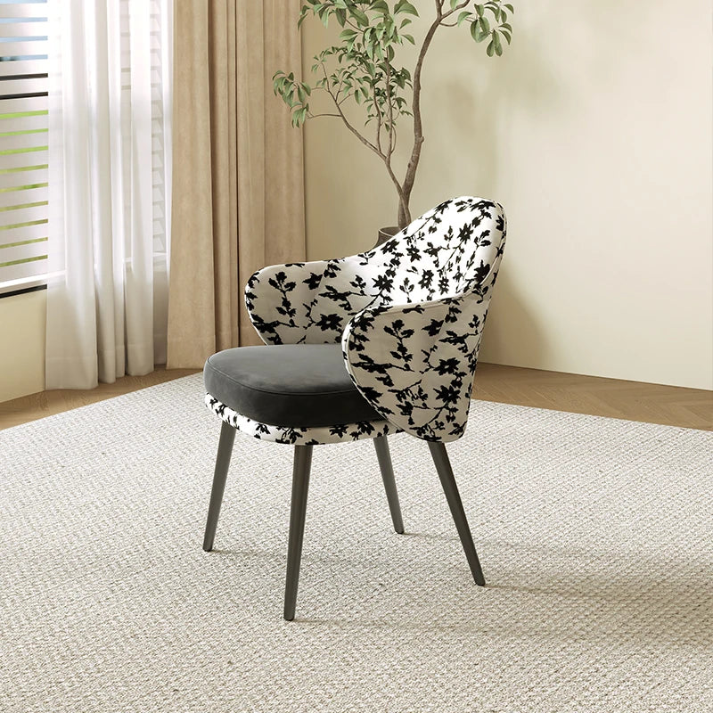 Chair with black floral pattern in a room with curtains and a plant
