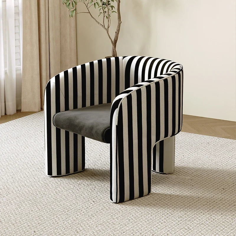 Modern chair with black and white striped pattern in a room with curtains and a plant.