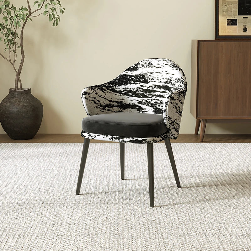 Modern chair with black and white patterned backrest in a room with a plant and cabinet.