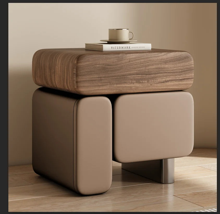 Wooden side table with a beige ottoman on a wooden floor.
