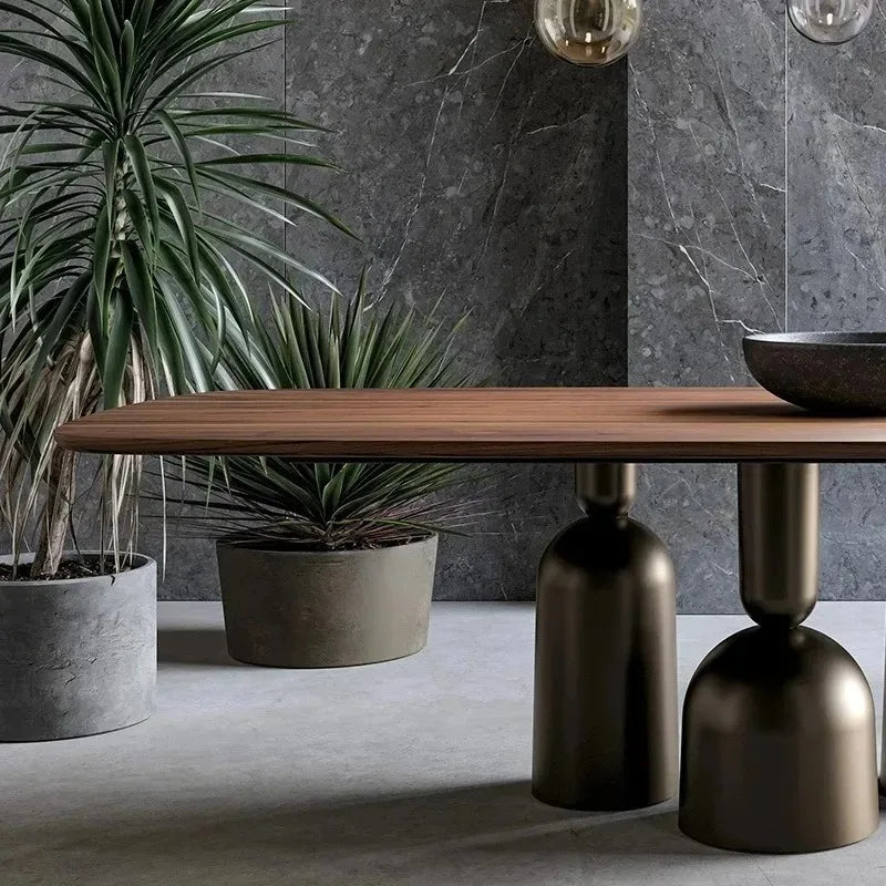 Modern interior with a wooden table, decorative vases, and potted plants against a gray stone wall.