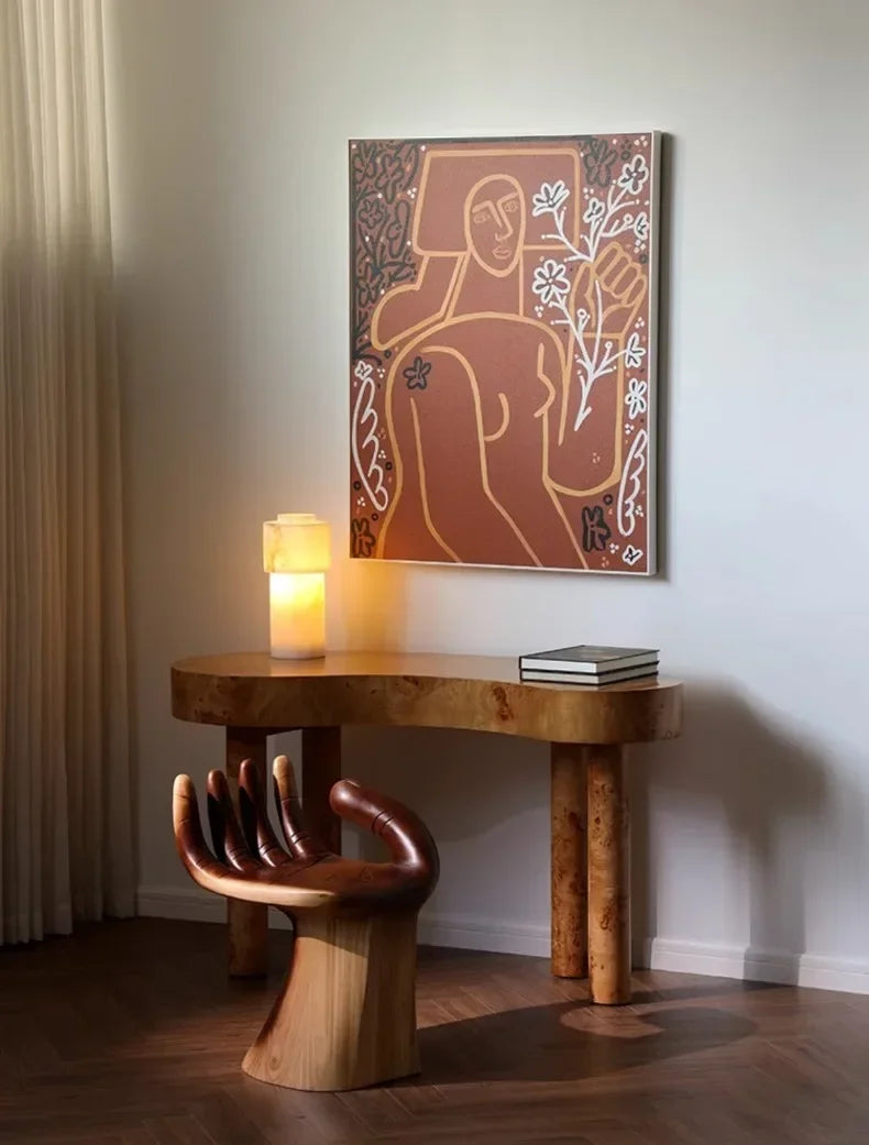 Wooden table with a unique chair design, candle, and abstract painting on the wall.