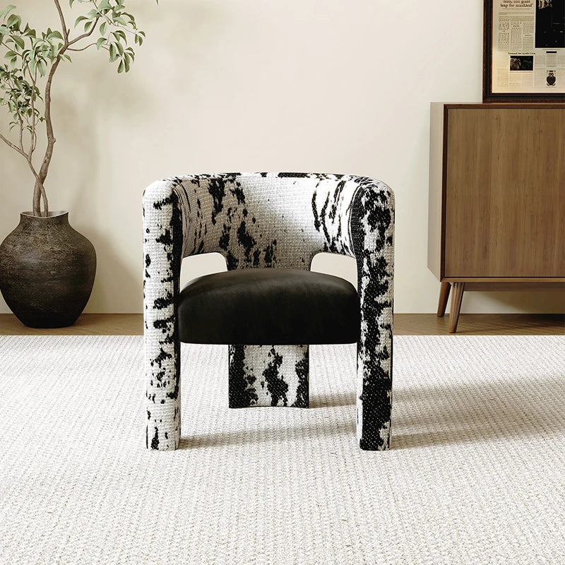 Chair with black and white pattern in a room with a plant and wooden cabinet.