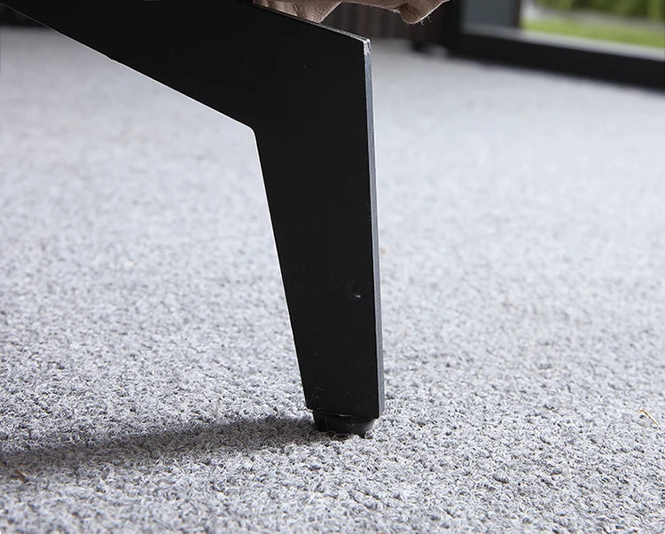 Close-up of a black metal leg on a gray carpet