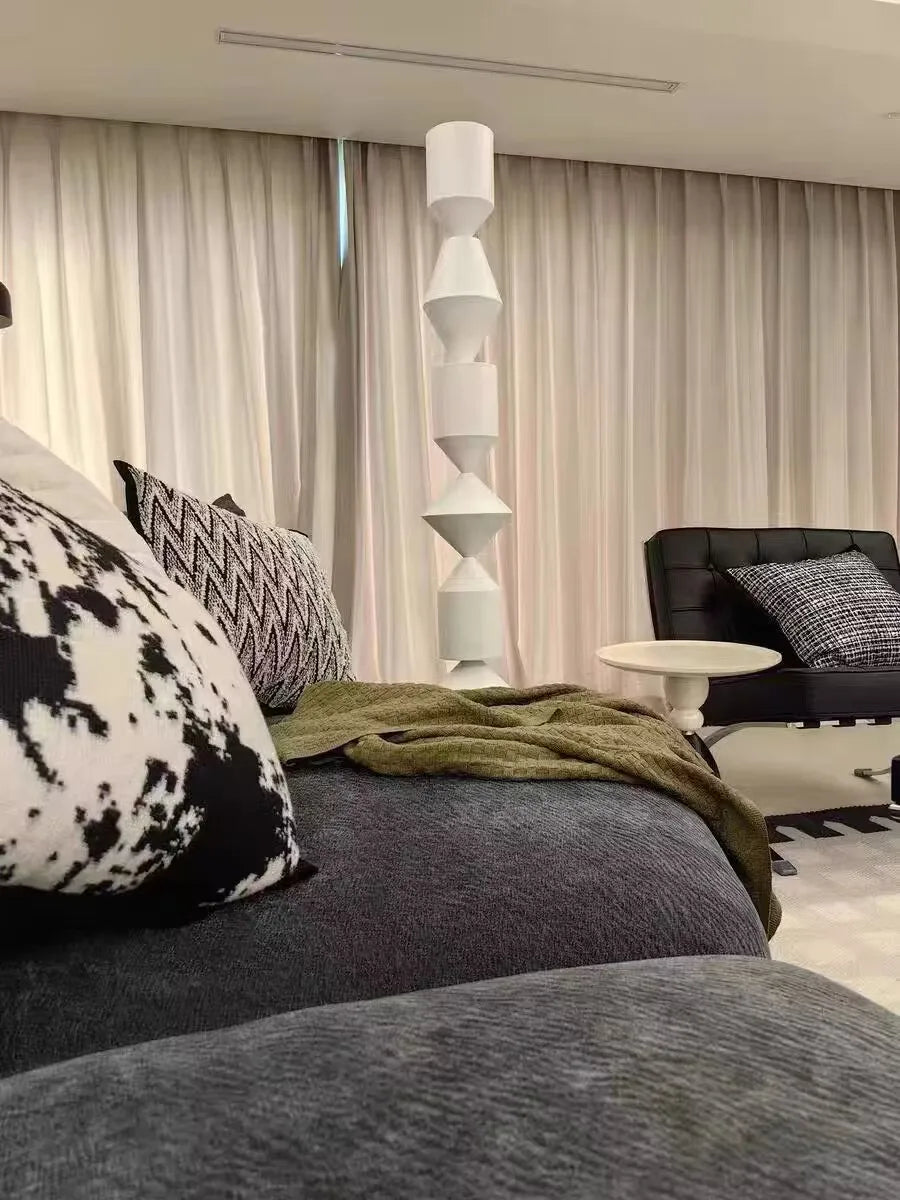 Modern living room with gray sofa, patterned cushions, and a black chair.