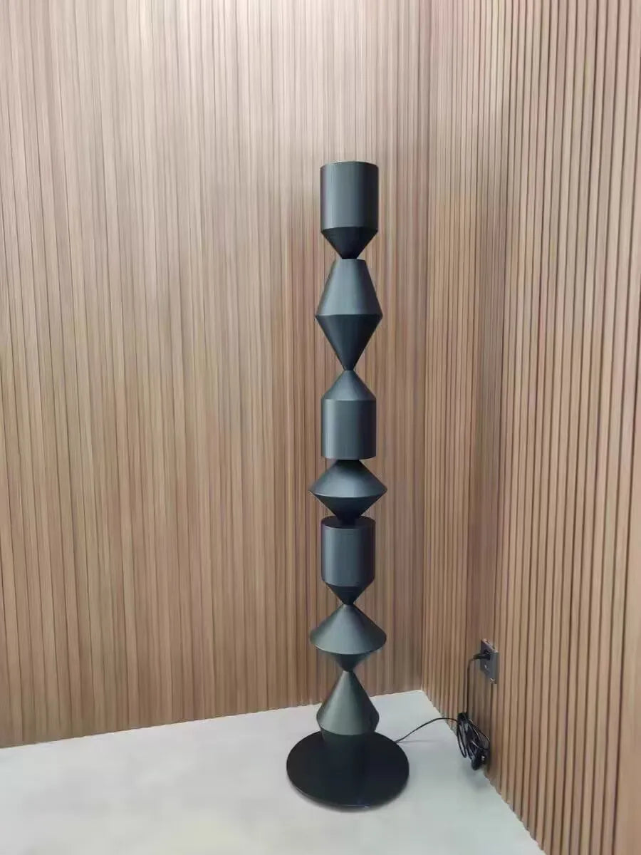 Decorative black floor lamp with geometric design against a wooden wall.