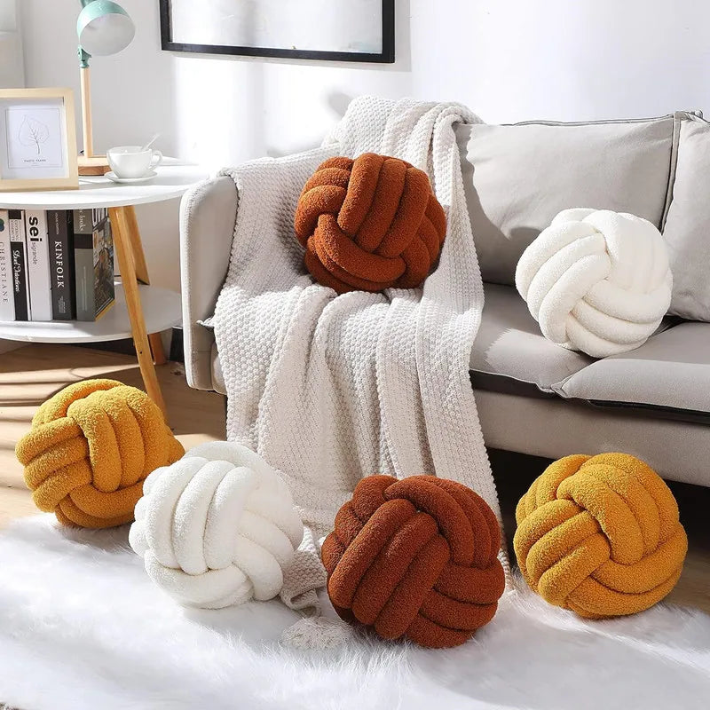 Decorative knot pillows in various colors on a sofa and floor.