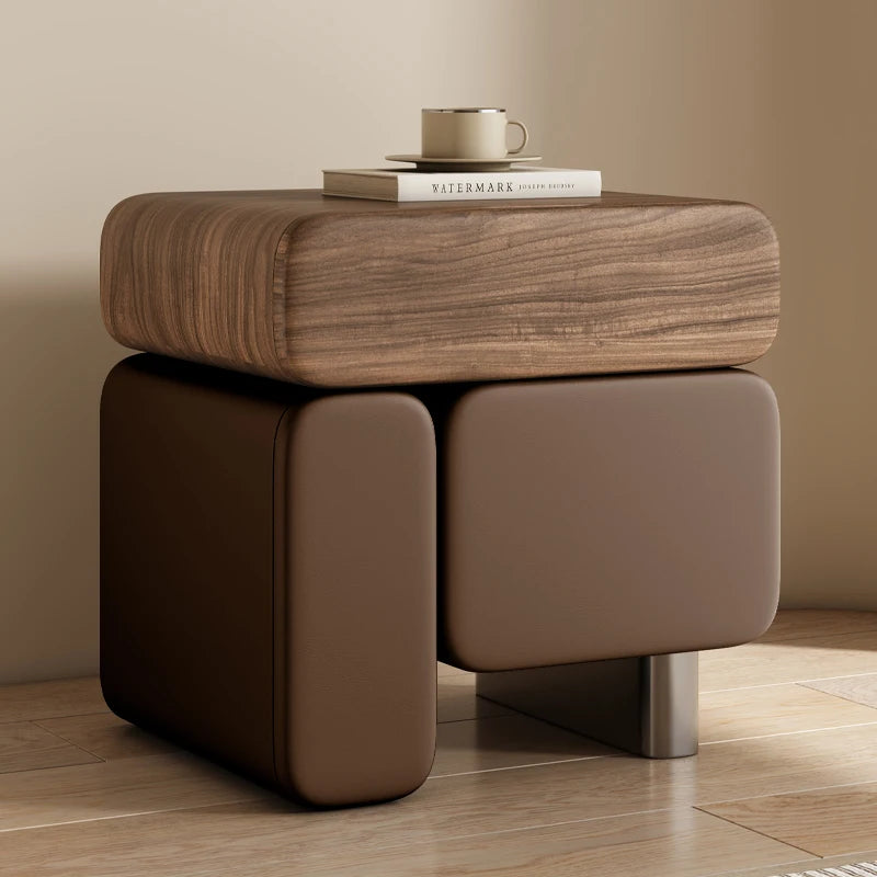 Brown wooden side table with a cup and books on top against a beige wall.