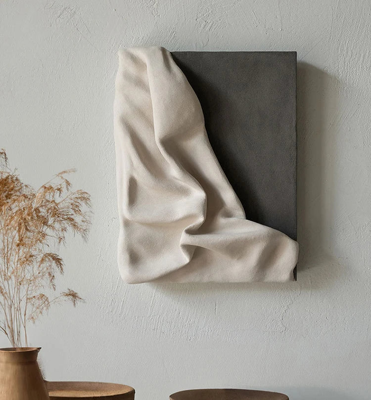 Textured wall art piece with draped fabric on a neutral background