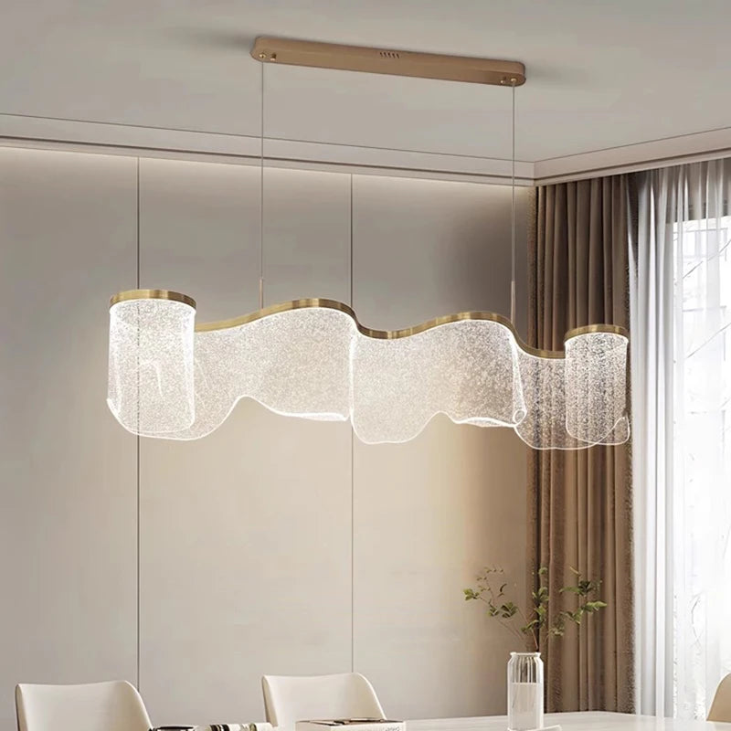 Modern chandelier hanging in a room with neutral walls and a window.