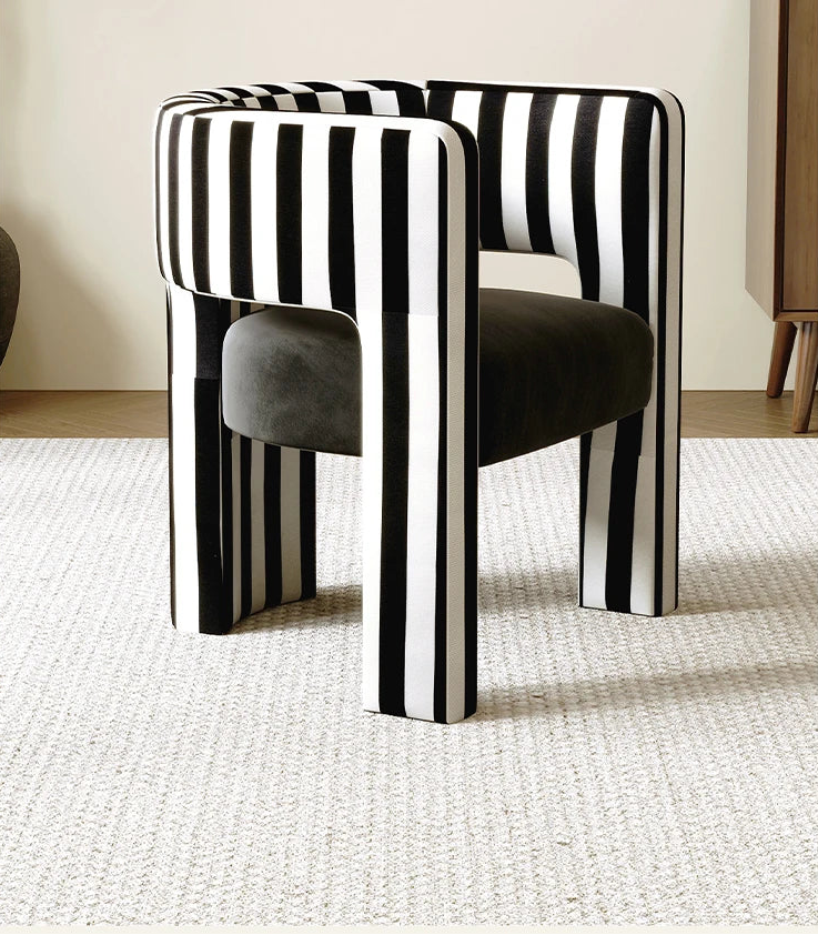 Modern chair with black and white striped backrest and gray cushion on a light carpet.