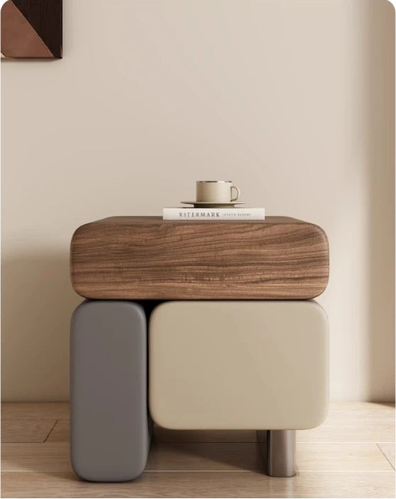 Modern side table with wooden top and gray base against a neutral wall.