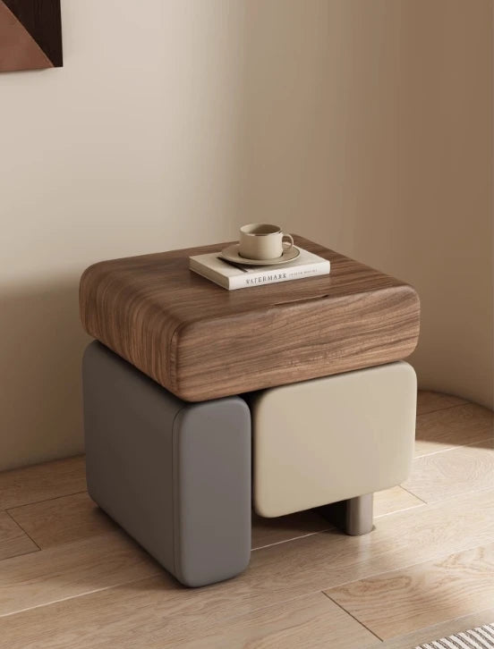 Wooden side table with a book and cup on a beige floor against a beige wall