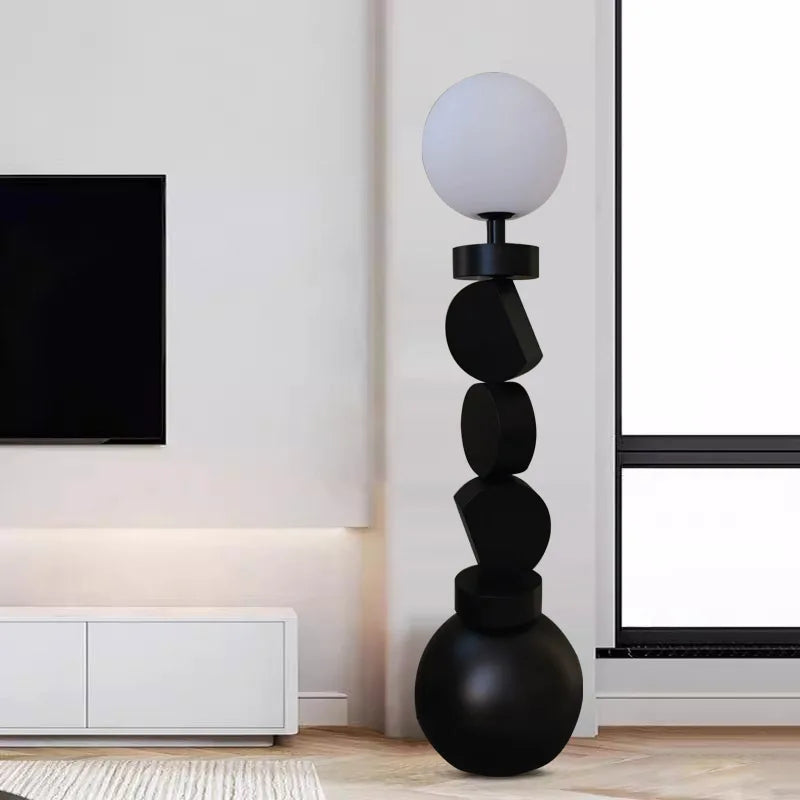 Modern black floor lamp with spherical design in a living room setting.