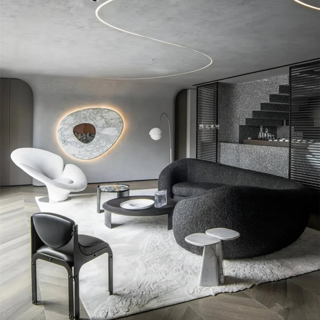Modern living room with gray sofa, black chair, and round coffee table.