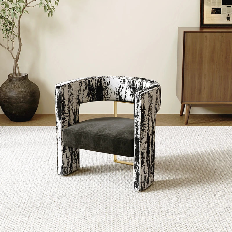 Modern chair with black and white distressed frame in a room with a plant and wooden cabinet.