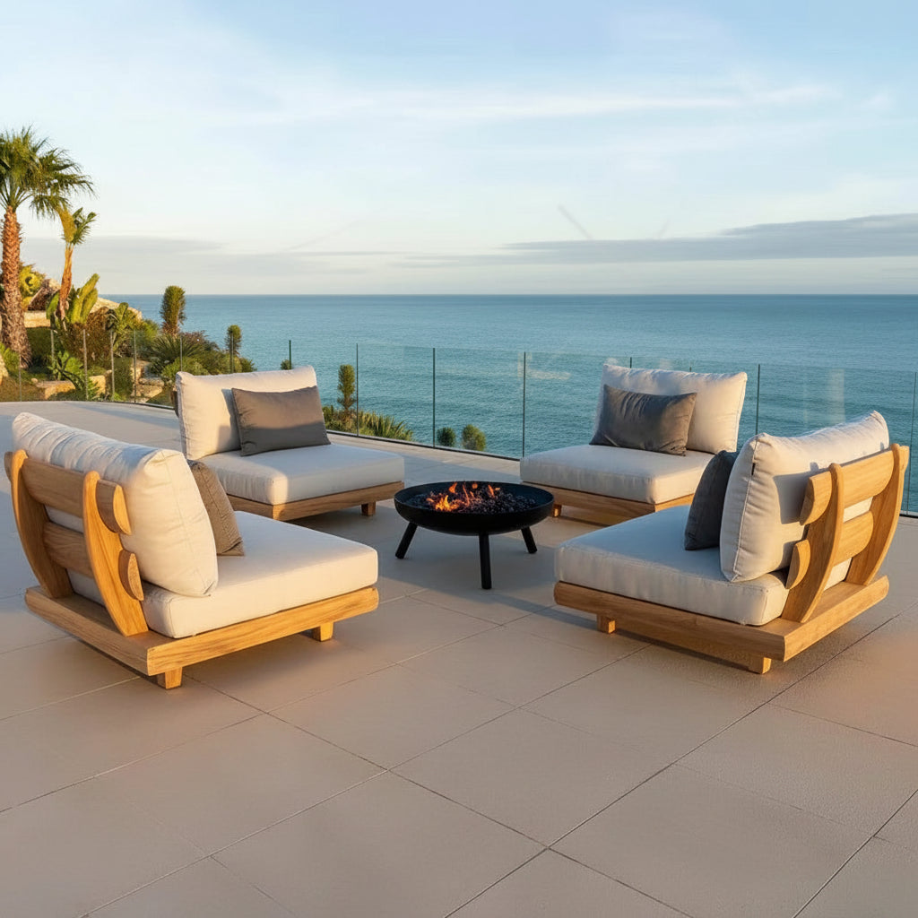 Outdoor patio set with wooden frames and white cushions overlooking a scenic ocean view.