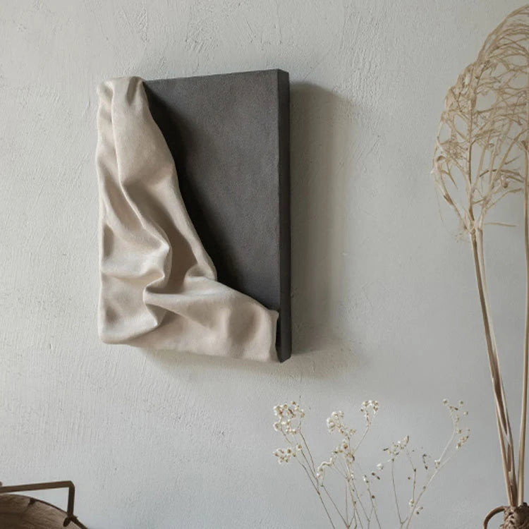 Textured wall art piece with draped fabric on a neutral background
