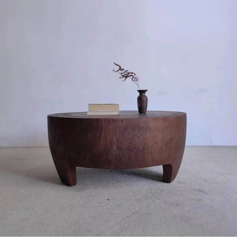 Wooden coffee table with a vase and book on a plain background