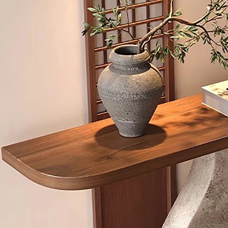 Gray ceramic vase on a wooden console table with a plant in the background