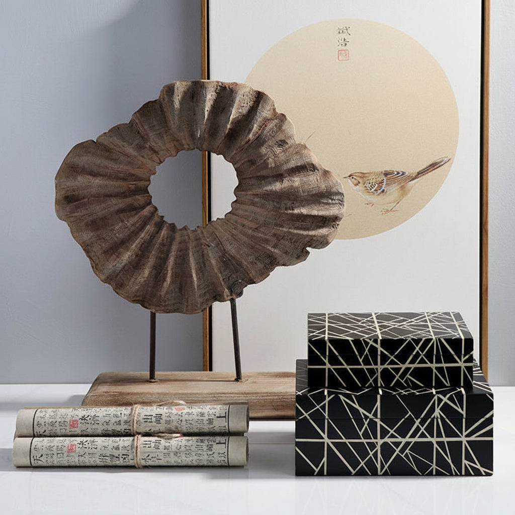 Decorative items including a shell sculpture, books, and a geometric box on a white surface with a painting in the background.