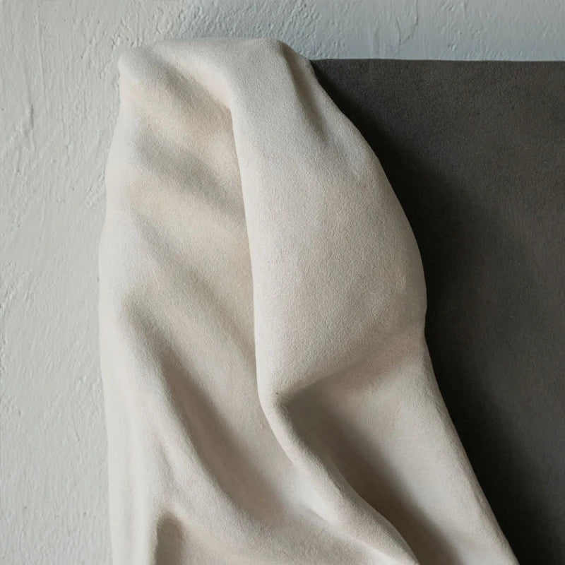 Beige fabric draped over a dark surface with a light gray background