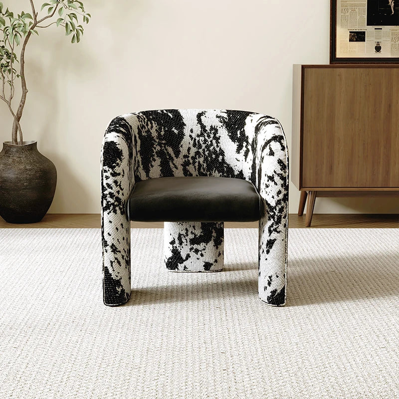 Chair with black and white pattern in a room with a plant and wooden cabinet.