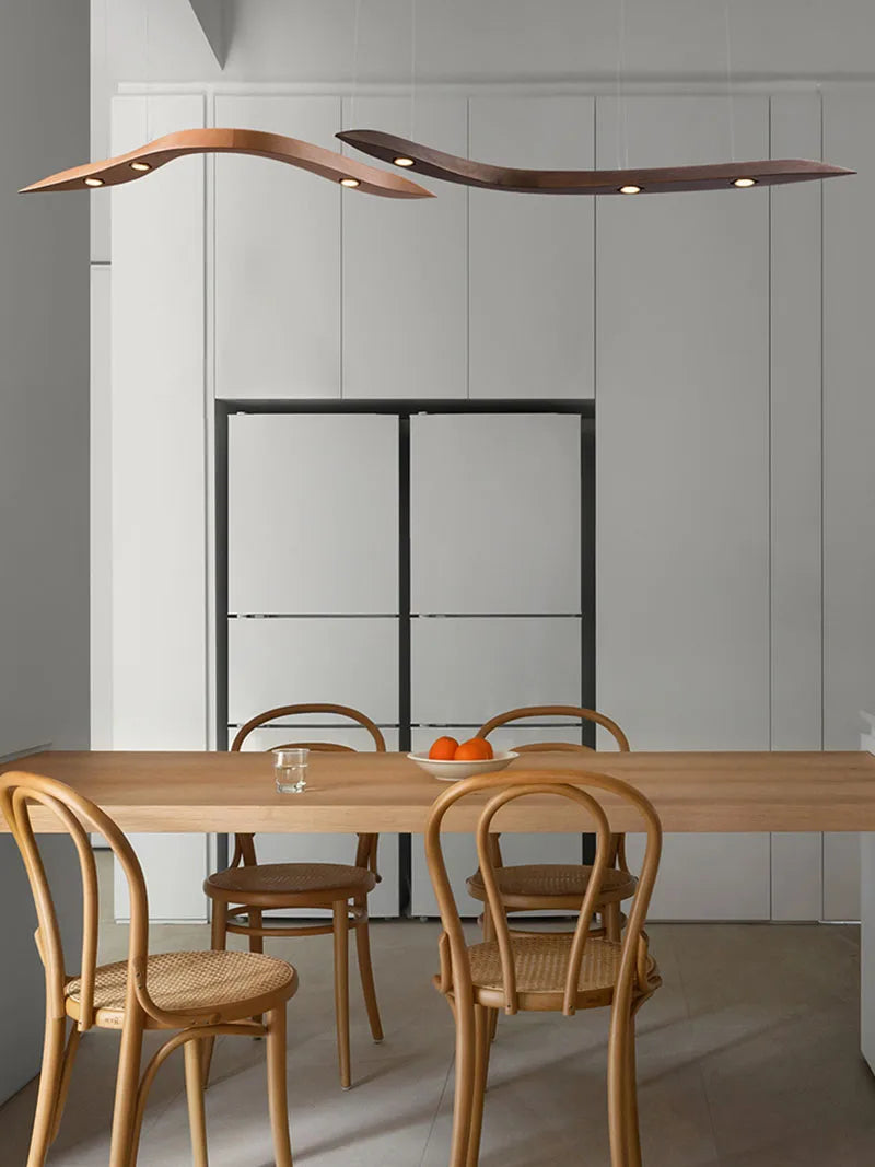 Modern dining area with wooden table and chairs, featuring a unique ceiling light fixture.