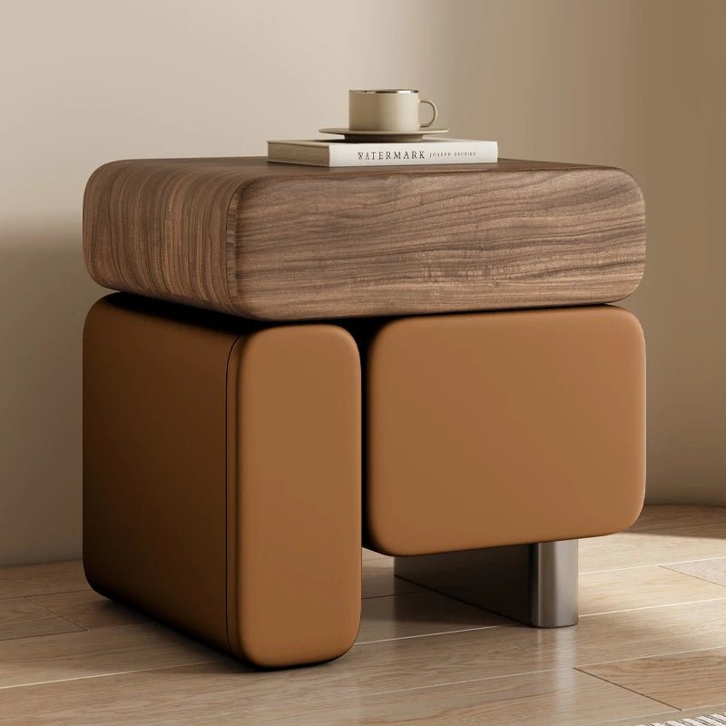 Brown wooden side table with a leather seat against a beige wall.