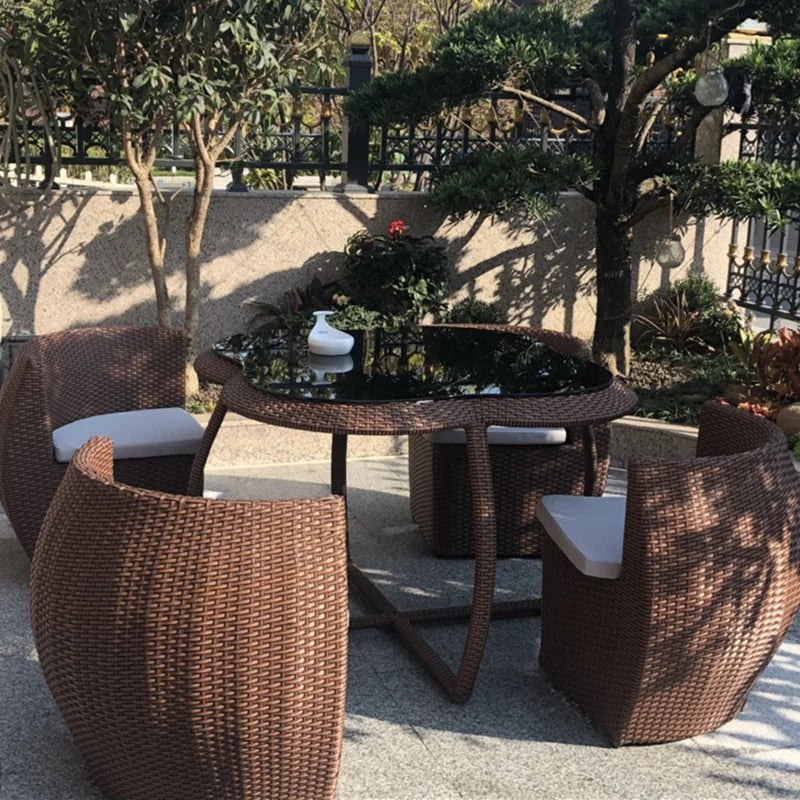Wicker outdoor furniture set with a table and chairs in a garden setting.