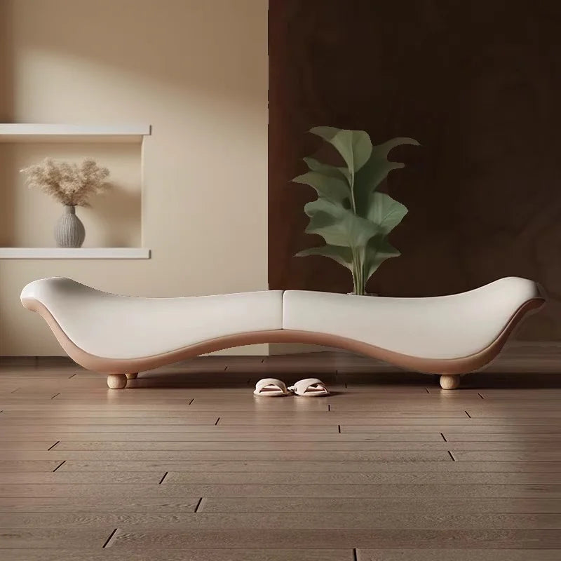 Modern white sofa with wooden legs in a minimalistic room with a plant and shelf.