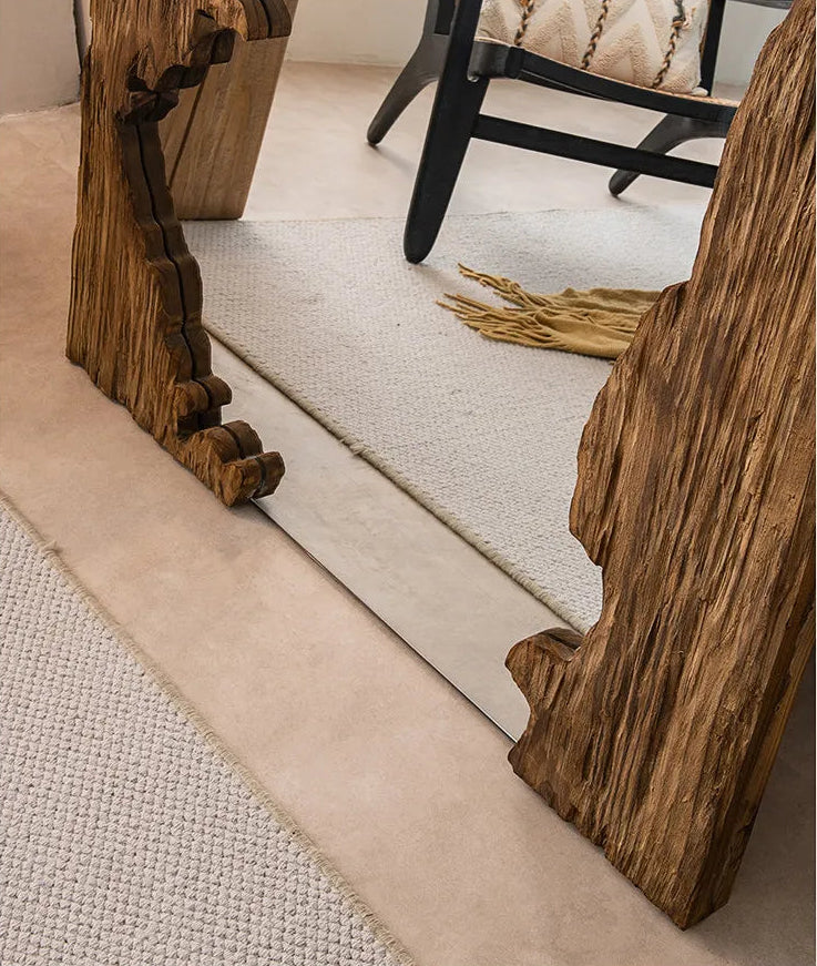 Wooden mirror stand with decorative design on a light-colored floor.